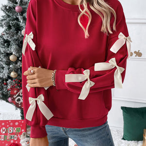 Rotes Sweatshirt mit cremefarbenen Schleifen an Ärmeln, getragen von einer Frau | Fashion Peak