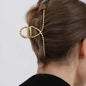 Goldene geflochtene Haarspange getragen im braunen Haar einer Frau | Fashion Peak