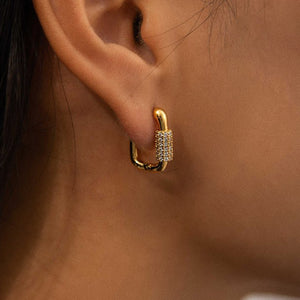 Goldener Ohrring mit Kettenglied-Design und Kristallen, getragen am Ohr einer Frau | Fashion Peak