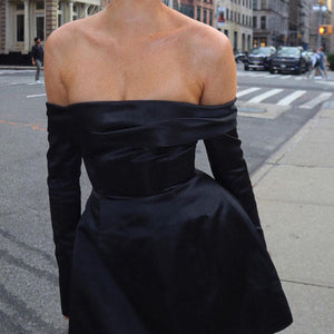 Schwarzes Off-Shoulder-Satinkleid mit Langarm, getragen von Frau auf Straße | Fashion Peak