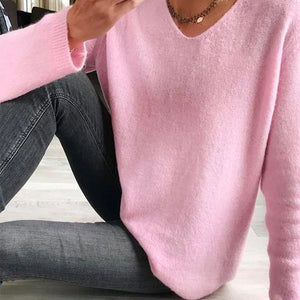 Rosa Strickpullover mit V-Ausschnitt, getragen von sitzender Frau auf Boden | Fashion Peak