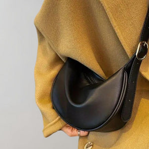 Schwarze Umhängetasche aus Kunstleder, halbrund, wird von Person getragen | Fashion Peak