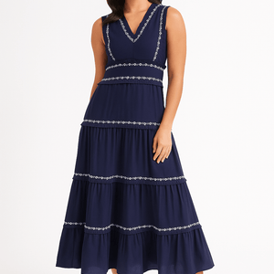 Frau trägt ärmelloses marineblaues Midikleid mit gestuftem Rock und Stickereidetails | Fashion Peak