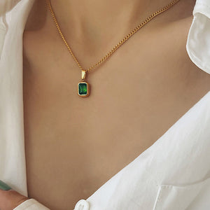 Goldkette mit grünem Stein-Anhänger, getragen von Frau in weißer Bluse | Fashion Peak