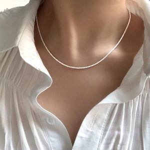 Zarte silberne Kette am Hals einer Frau, weißes Hemd getragen | Fashion Peak