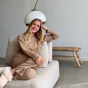 Frau trägt beigefarbenes geripptes Zweiteiler-Set, sitzend auf Sofa | Fashion Peak