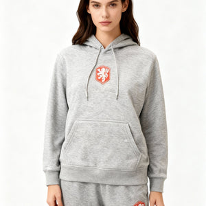 Frau trägt grauen Kapuzenpullover mit Jogginghose und rotem Wappenaufnäher | Fashion Peak