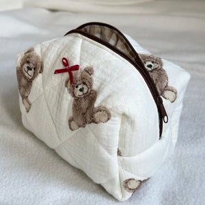 Cremefarbene gesteppte Kosmetiktasche mit Teddybär-Print und roter Schleife, freistehend | Fashion Peak