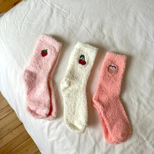 Drei flauschige Socken in Rosa und Weiß mit Früchte-Stickerei, flach liegend | Fashion Peak