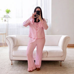Rosa Schlafanzug mit Rüschen, langärmelig, getragen von Frau vor Sofa | Fashion Peak