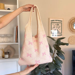 Gehäkelte Shopper Tasche in Creme mit rosa Schleifenmuster, in Hand gehalten | Fashion Peak
