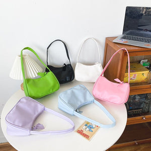 Sieben Baguette-Taschen aus Kunstleder in Pastellfarben, flach auf Tisch liegend | Fashion Peak